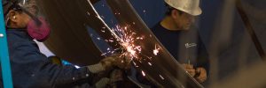 Worker fabricates metal with angle grinder